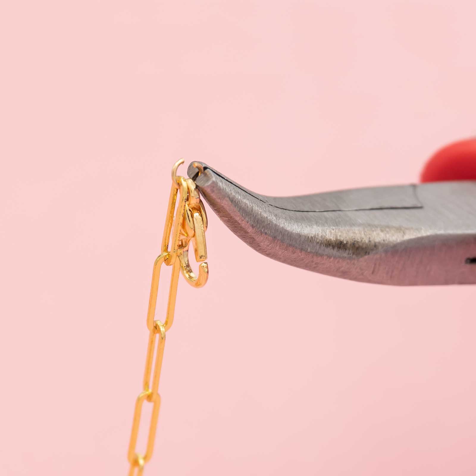 goldfarbener Karabiner und Kette hängen in einem offenen Biegering Closeup