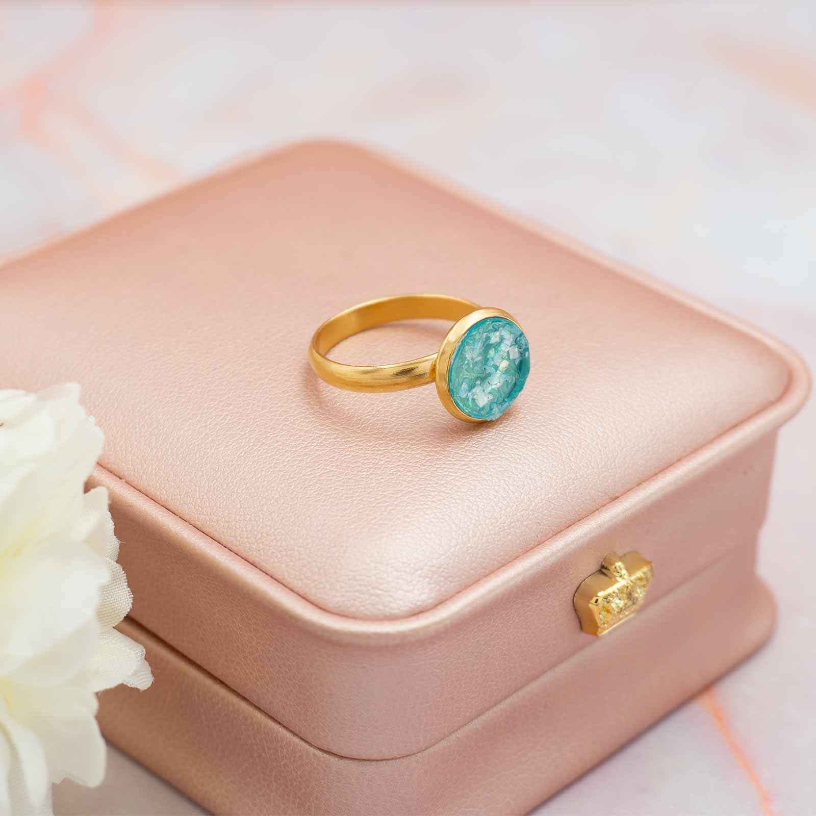Goldfarbener Ring mit türkisem Cabochon in einem Schmuckkästchen