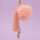 Rosa Fellbommel als Taschenanhänger an einem goldfarbenen Karabiner, daneben eine Quaste in Rosa und an feiner Gliederkette zwei goldfarben gefasste Muscheln, frei hängend vor fliederfarbenem Hintergrund.