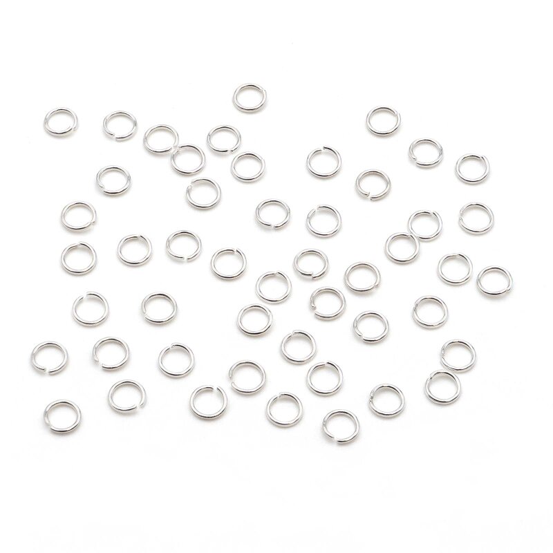 Viele silberfarbene Biegeringe aus 304 Edelstahl liegen gleichmäßig verteilt auf weißem Untergrund. Jeder Ring ist an einer Stelle offen, die glänzende Oberfläche spiegelt das Licht an den Rundungen.