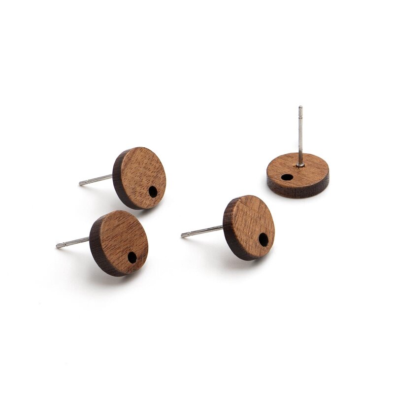 Vier Ohrstecker-Rohlinge aus Walnussholz auf weißem Grund. Drei liegen flach und zeigen die Maserung und das seitliche Bohrloch, einer steht aufrecht auf seinem Edelstahlstift.