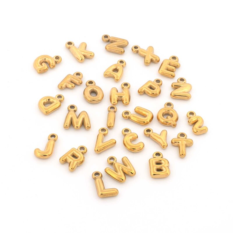 Alle 26 Buchstaben-Anhänger von A bis Z locker gestreut auf weißem Grund, gewölbte Großbuchstaben aus 304 Edelstahl mit IP-Beschichtung in Gold, jeder mit angegossener Aufhängung und Fädelloch