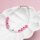 Armband aus kleinen weißen Perlen mit rosa Buchstabenperlen für LOVE und HOPE, dazwischen eine weiße Sonderzeichenperle mit schwarzem Und-Zeichen, mit Karabinerverschluss, in einer weißen Schale vor rosa Hintergrund